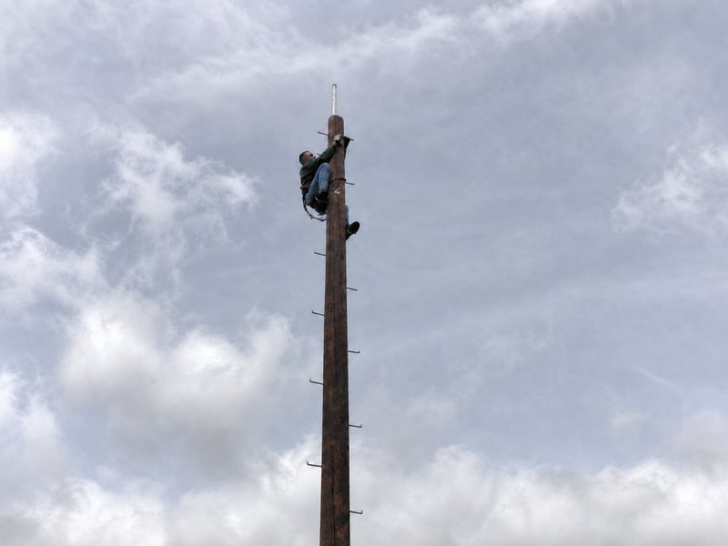 Bill Armour secured near the top of a communications pole during installation work.