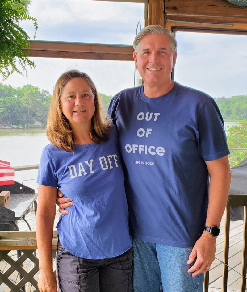 Bill and Nancy Armour smiling together on a screened porch overlooking the water.